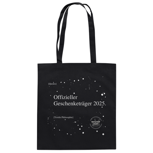 Schwarzer Jutebeutel von „Sag’s auf Stoff“ mit weißer Aufschrift "Offizieller Geschenketräger 2025.", Weißen Schneeflocken im Hintergrund und Logo "Sag´s auf Stoff". Perfekt als Geschenk.