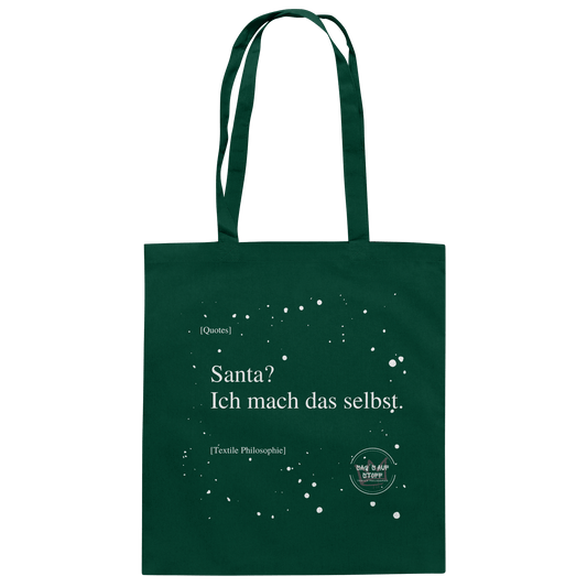 Grüner Jutebeutel von „Sag’s auf Stoff“ mit weißer Aufschrift "Santa? Ich mach das selbst.", Weißen Schneeflocken im Hintergrund und Logo "Sag´s auf Stoff". Perfekt als Geschenk.
