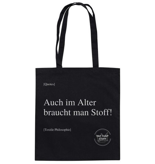 Schwarzer Jutebeutel mit weißer Aufschrift "Auch im Alter braucht man Stoff" und Logo "Sag´s auf Stoff"