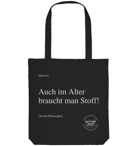 Schwarzer Jutebeutel mit weißer Aufschrift "Auch im Alter braucht man Stoff" und Logo "Sag´s auf Stoff"